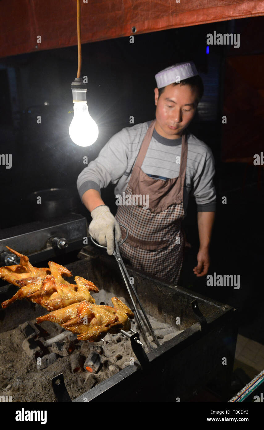 Un hombre musulmán chino de pollos de asar más charcoals. Foto de stock