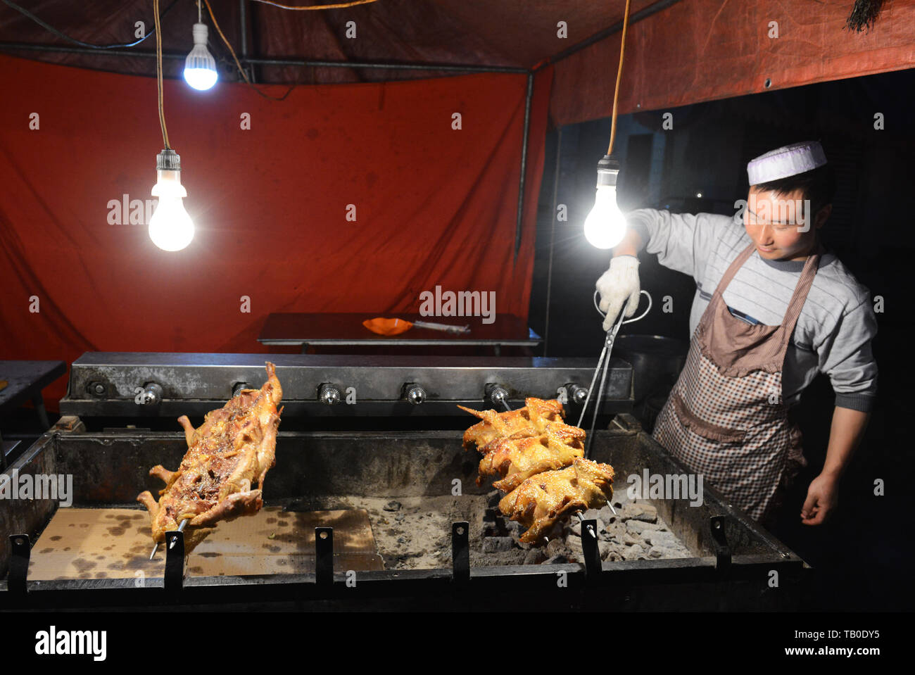 Un hombre musulmán chino de pollos de asar más charcoals. Foto de stock