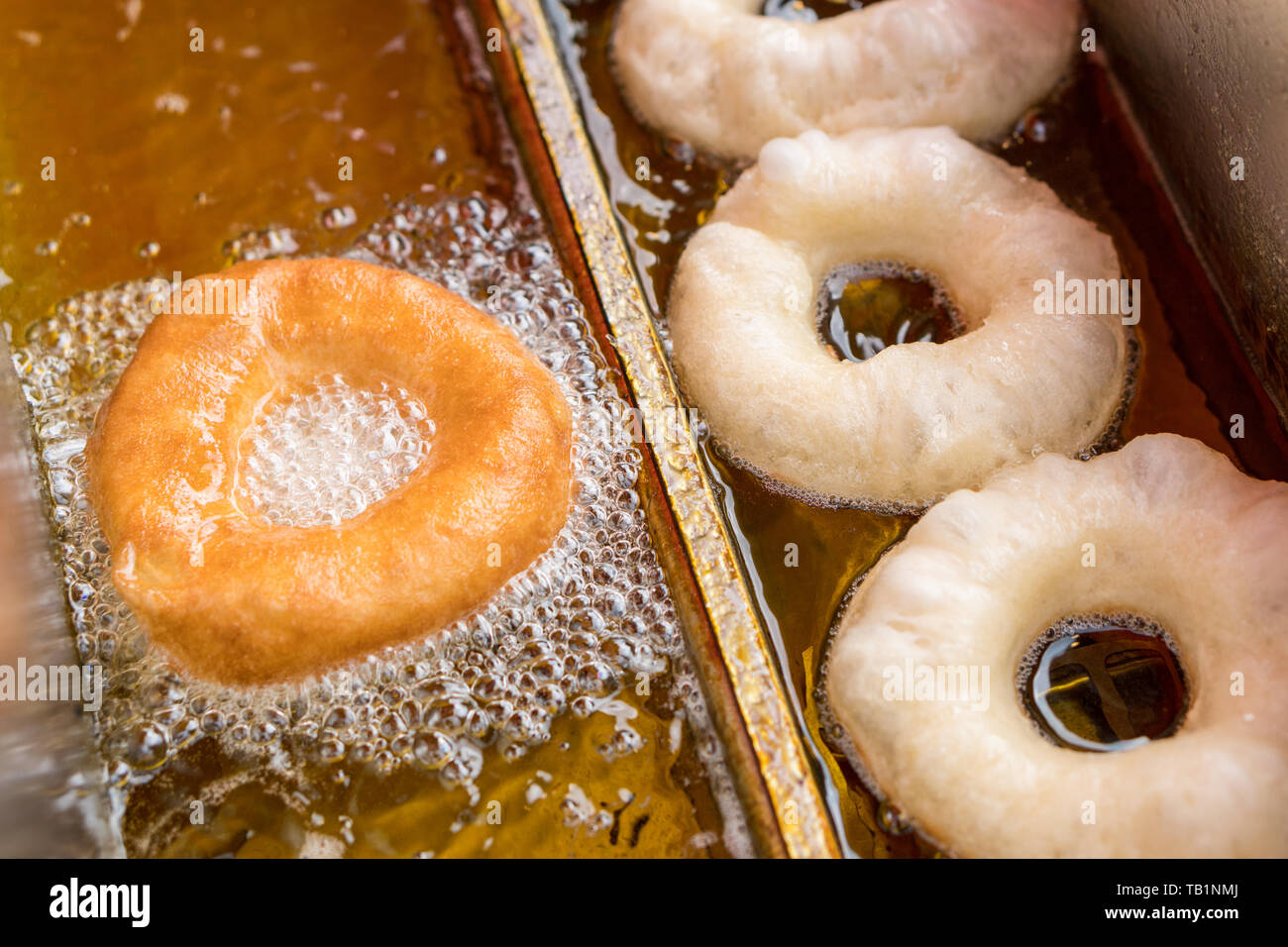 Máquina de hacer donuts donuts de freír en aceite caliente. Concepto de  comida basura malsana Fotografía de stock - Alamy