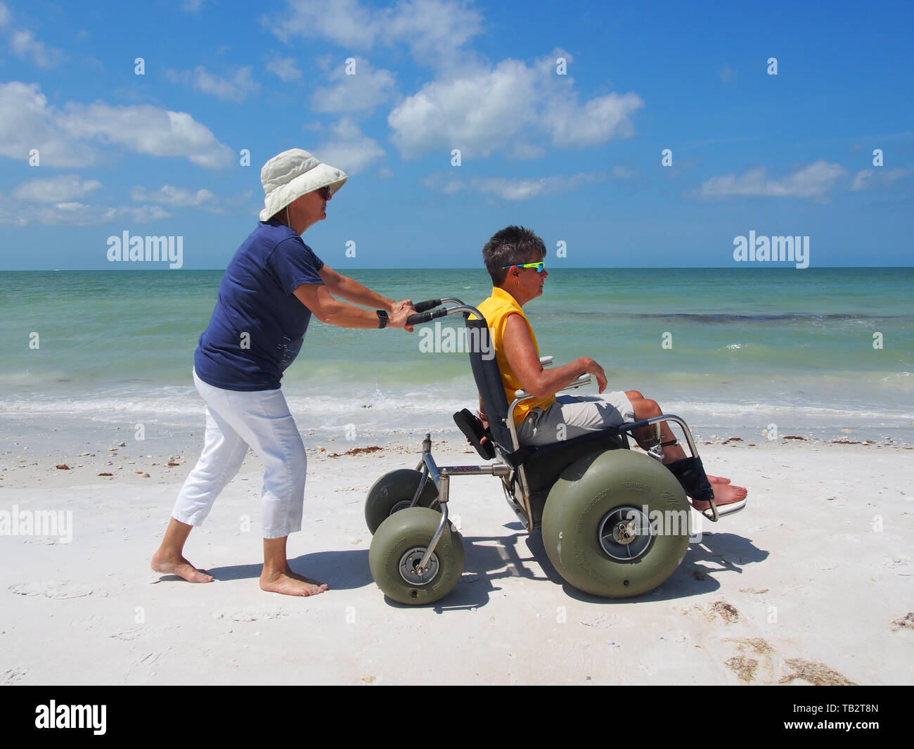 Mujer discapacitada en silla de ruedas de playa goza del sol y la arena en Honeymoon Island State Park, en Dunedin, Florida, EE.UU., 10 de mayo de 2019, © Katharine Andrioti Foto de stock