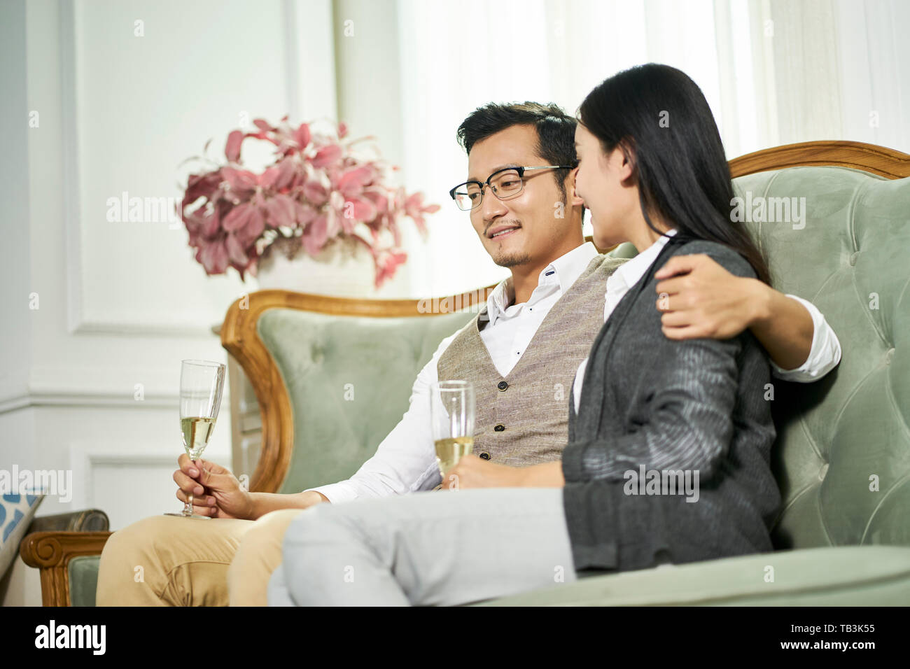 Jóvenes asiáticos amorosa pareja sentada en la cama hablando charlando en casa Foto de stock