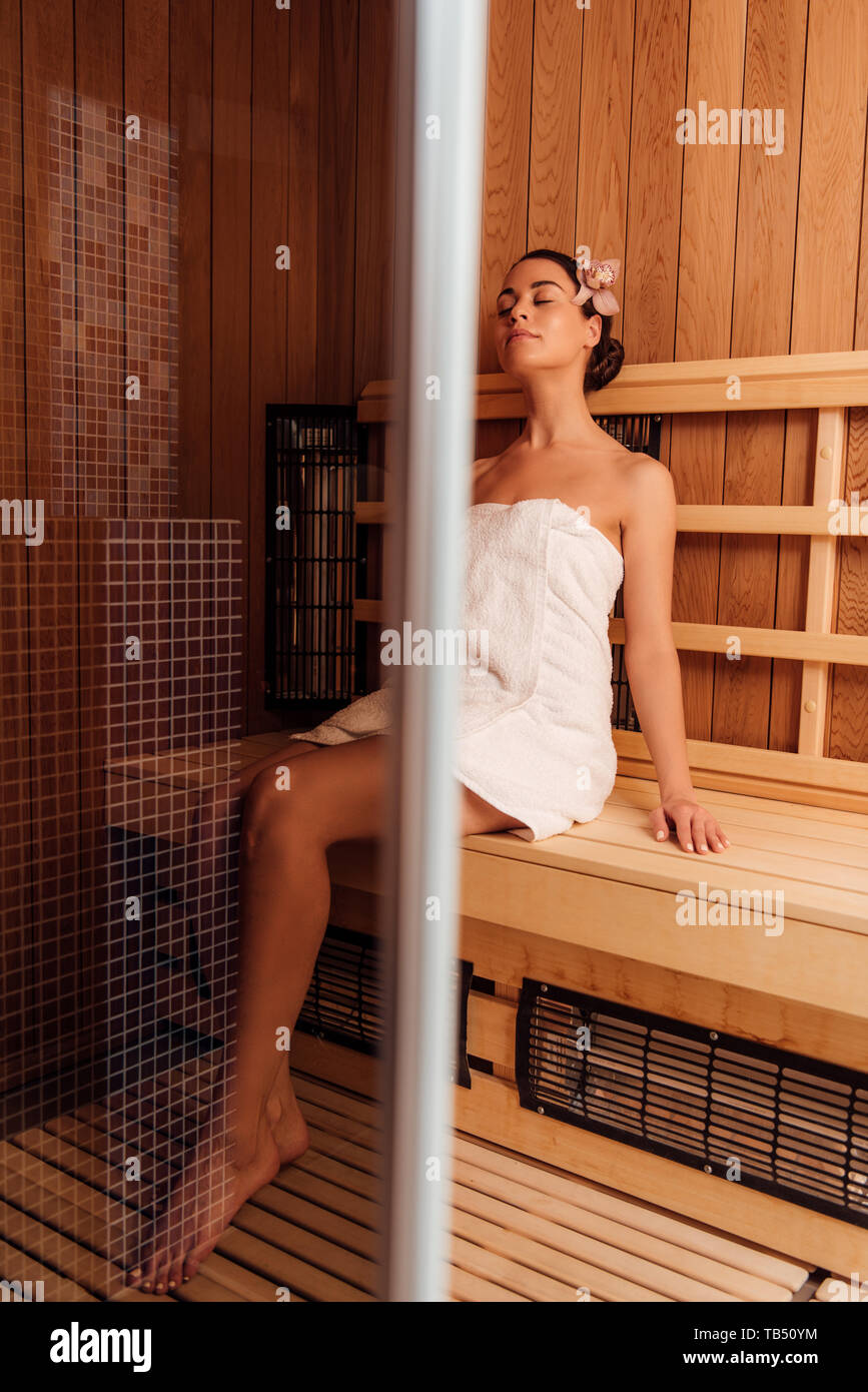Mujer desnuda relajada en toalla sentado con los ojos cerrados en sauna  Fotografía de stock - Alamy