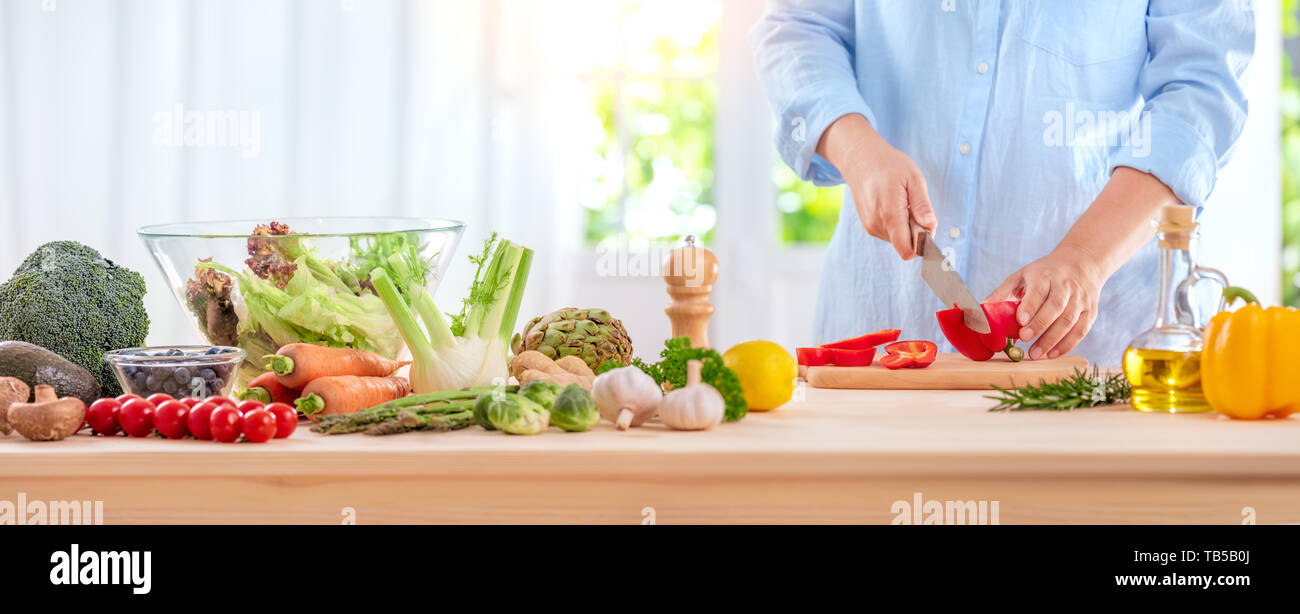 Cocinar, alimentos y INICIO CONCEPTO - Cierre de mano femenina cortando pimienta sobre la tabla de cortar en casa Foto de stock
