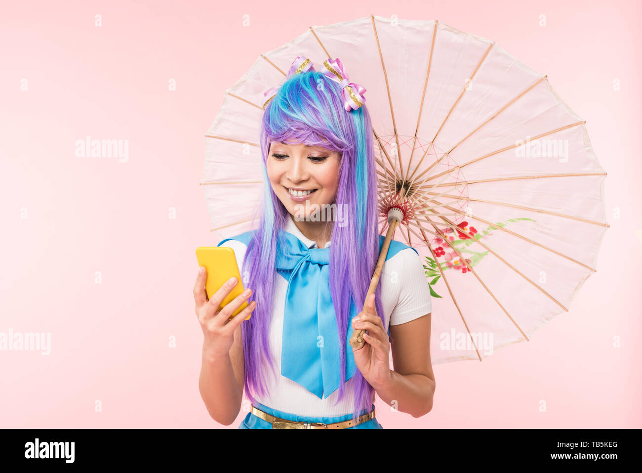 Anime asiático Chica sujetando el papel paraguas y smartphone usando  aislado en rosa Fotografía de stock - Alamy