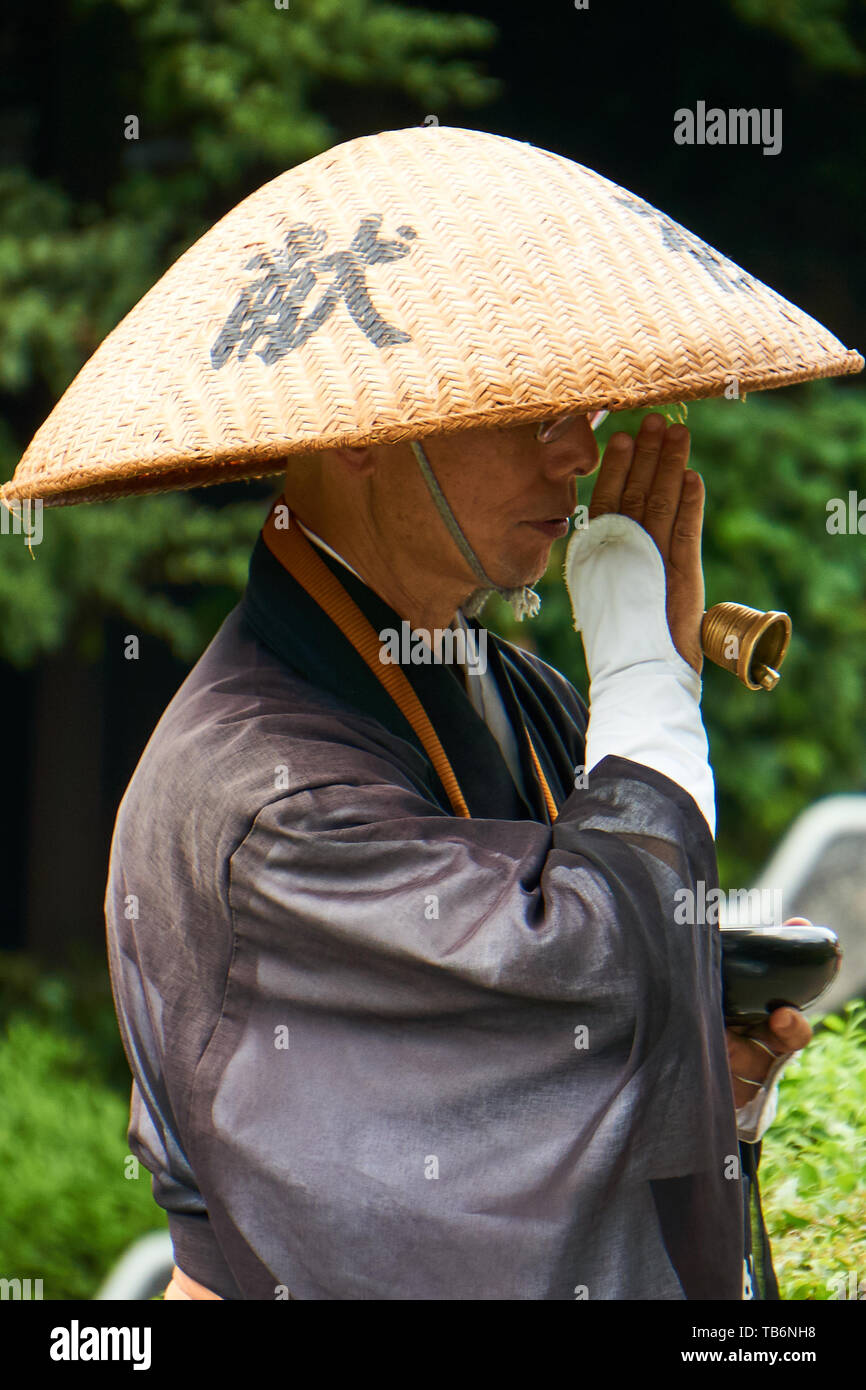 Un monje japonés en gran sombrero de paja y la tradicional vestimenta negra  batas sosteniendo una campana ora y pide donaciones Fotografía de stock -  Alamy