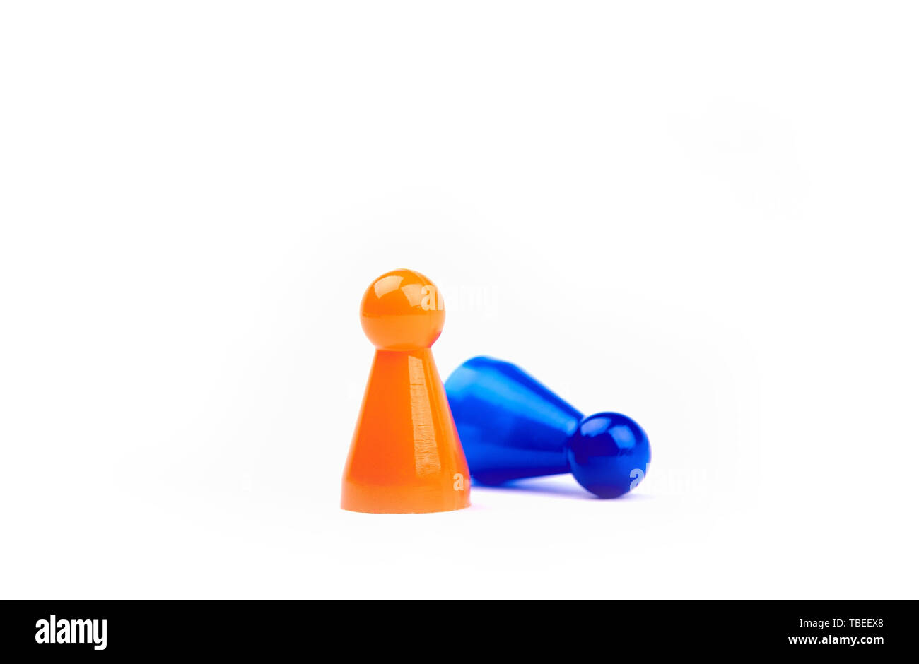 Dos de juguete de plástico naranja - Juego permanente de figurillas como ganador y figurita azul radica como perdedor - aisladas sobre fondo blanco. Foto de stock