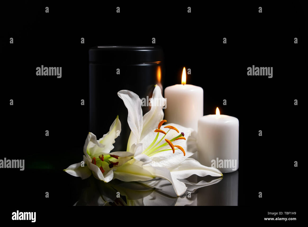 Urna funeraria, el encendido de velas y flores de lis sobre fondo oscuro  Fotografía de stock - Alamy