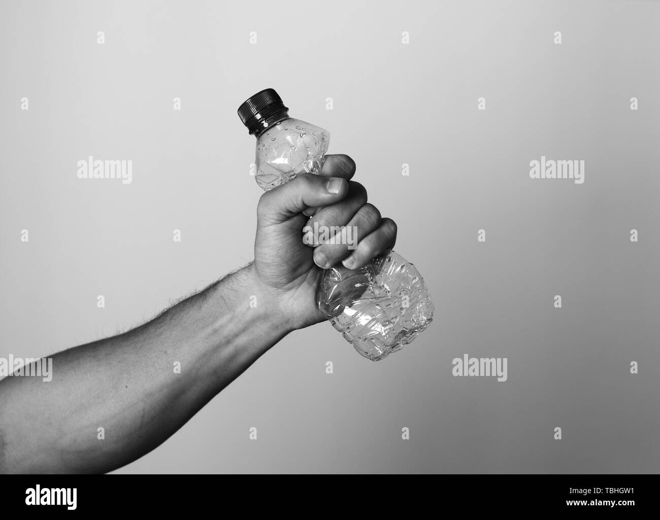 La mano que aprieta botella de plástico que representa el reciclaje y la polución. Foto de stock