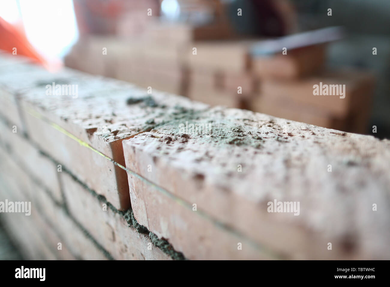 Se centran en los ladrillos sentado en una habitación grande con gran habilidad y destreza. Gran construcción niveló con cadena especial hecha de materiales fuertes y duraderos. Foto de stock