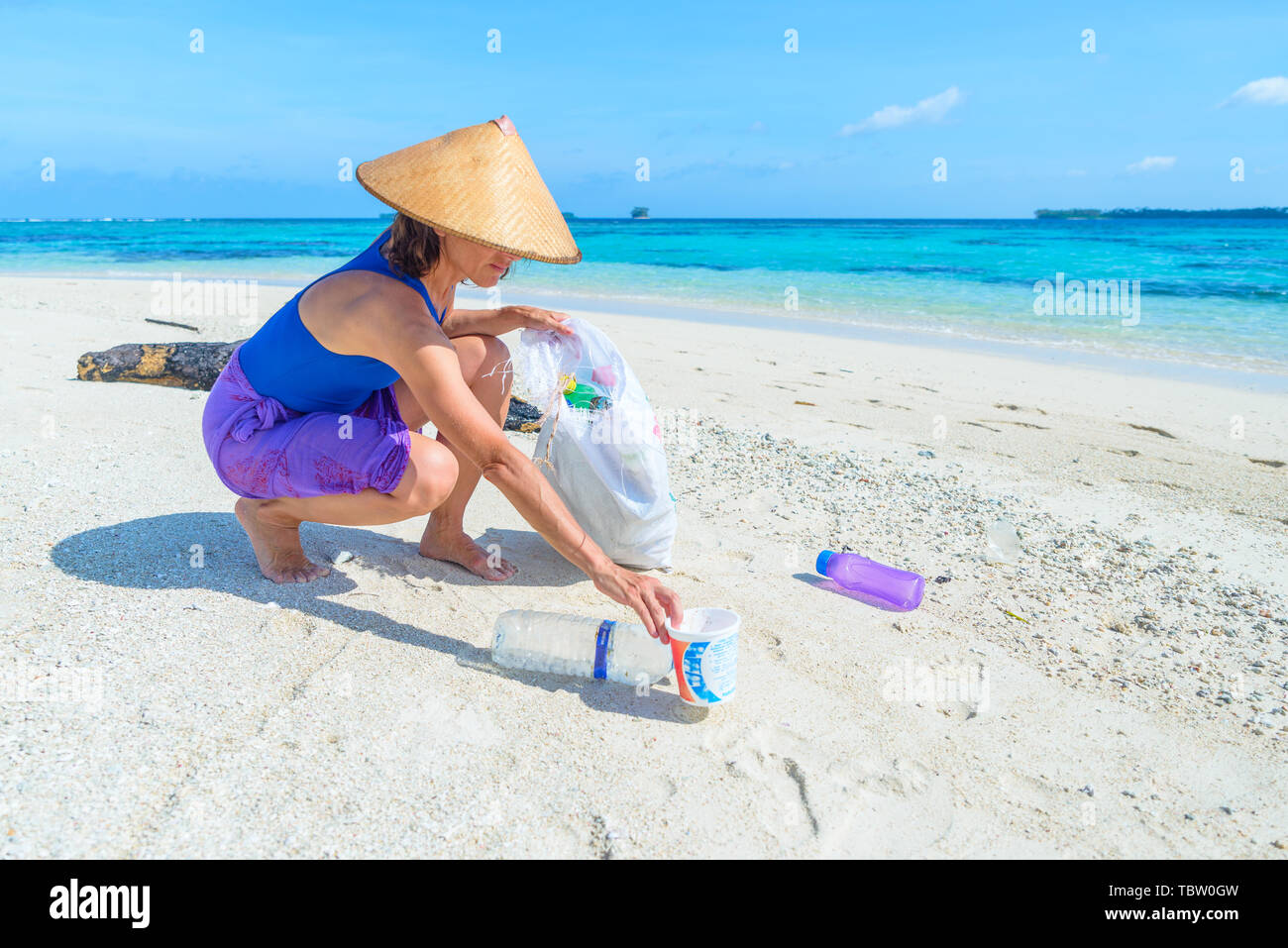 Mujer recolectando botellas de plástico en la hermosa playa tropical, mar turquesa, día soleado, reciclar la basura el concepto, la protección del medio ambiente. Foto de stock
