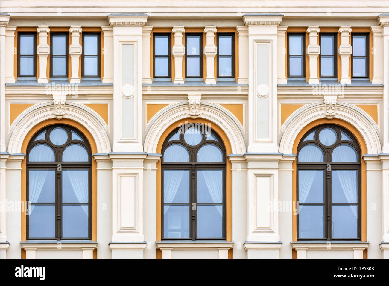 Ventanas con un arco en la fachada de la pared naranja de un edificio  residencial con columnas en la parte vieja de la ciudad de Riga. Desde la  ventana de la serie