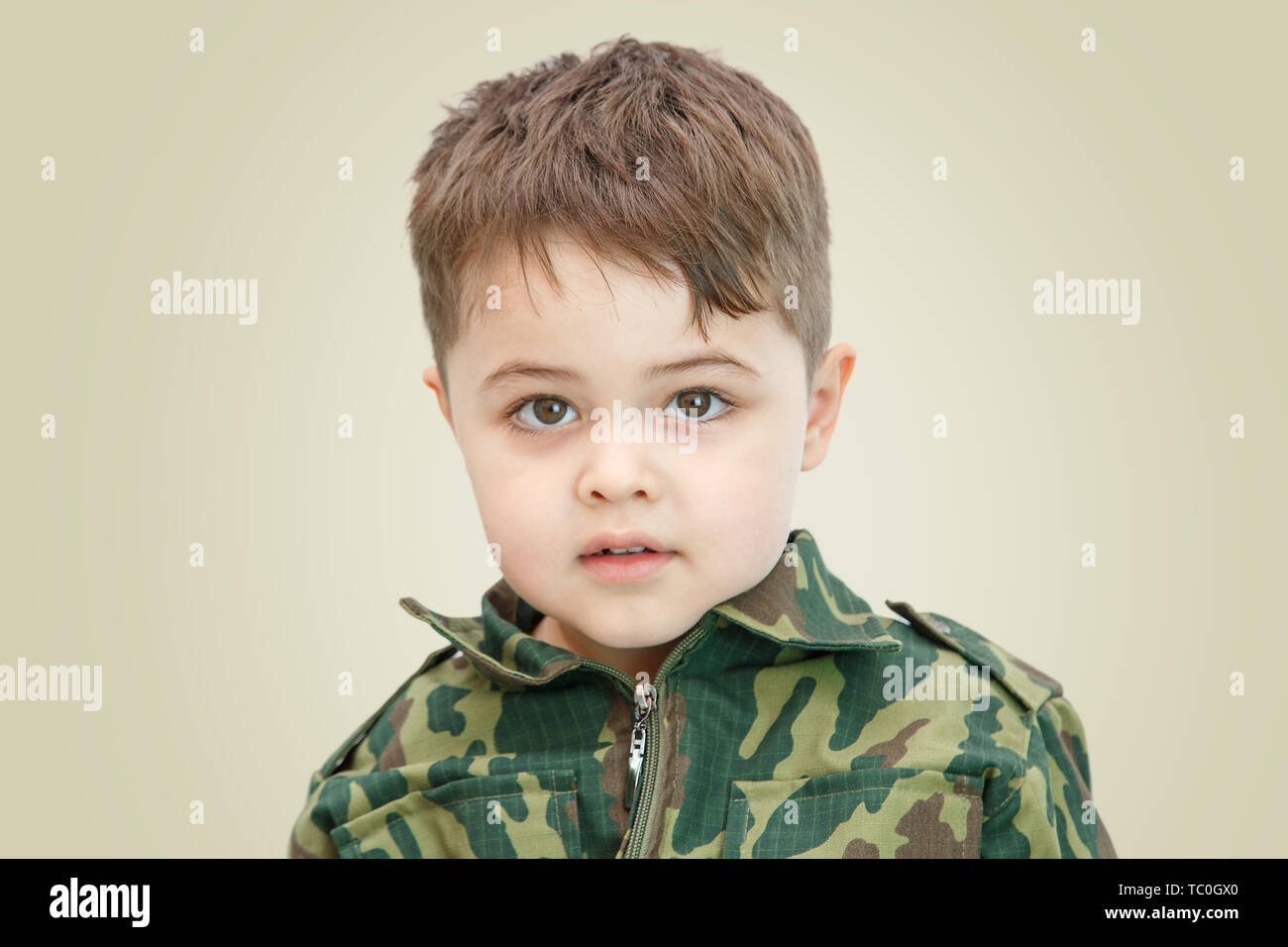 Poco muchacho en ropa militar y con armas de juguete en una luz de fondo aislado Fotografía de stock - Alamy