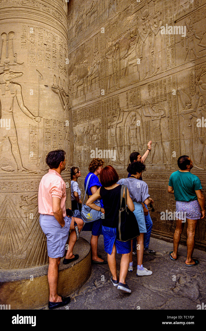 Egipto: Los turistas se muestran jeroglíficos y decoración en bajorrelieve en un templo en el nilo. Foto: © Simon Grosset. Archivo: Imagen digitalizada de una o Foto de stock