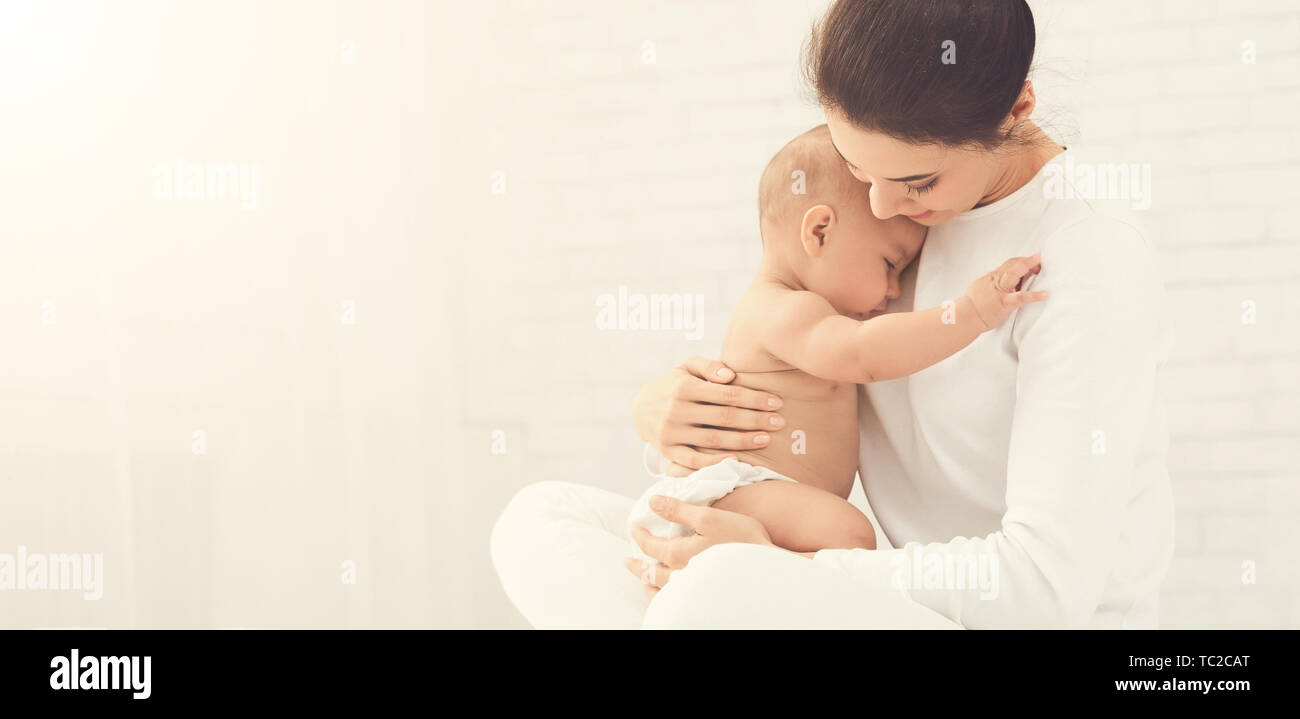 La joven madre sostiene a su hijo recién nacido en manos Foto de stock