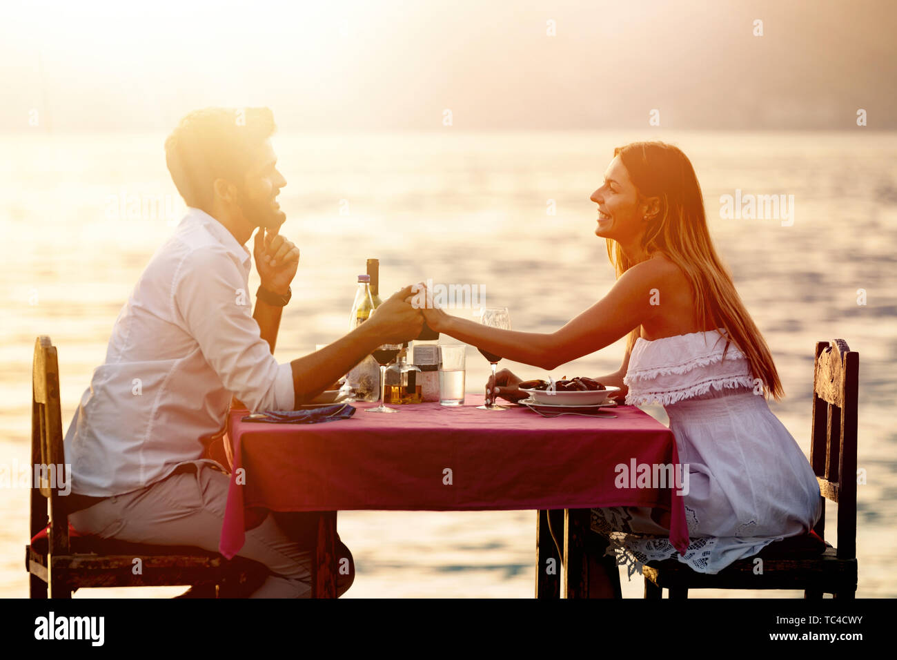 La gente, las vacaciones, el amor y el romance concepto. Pareja joven disfrutando de una cena romántica en la playa. Foto de stock