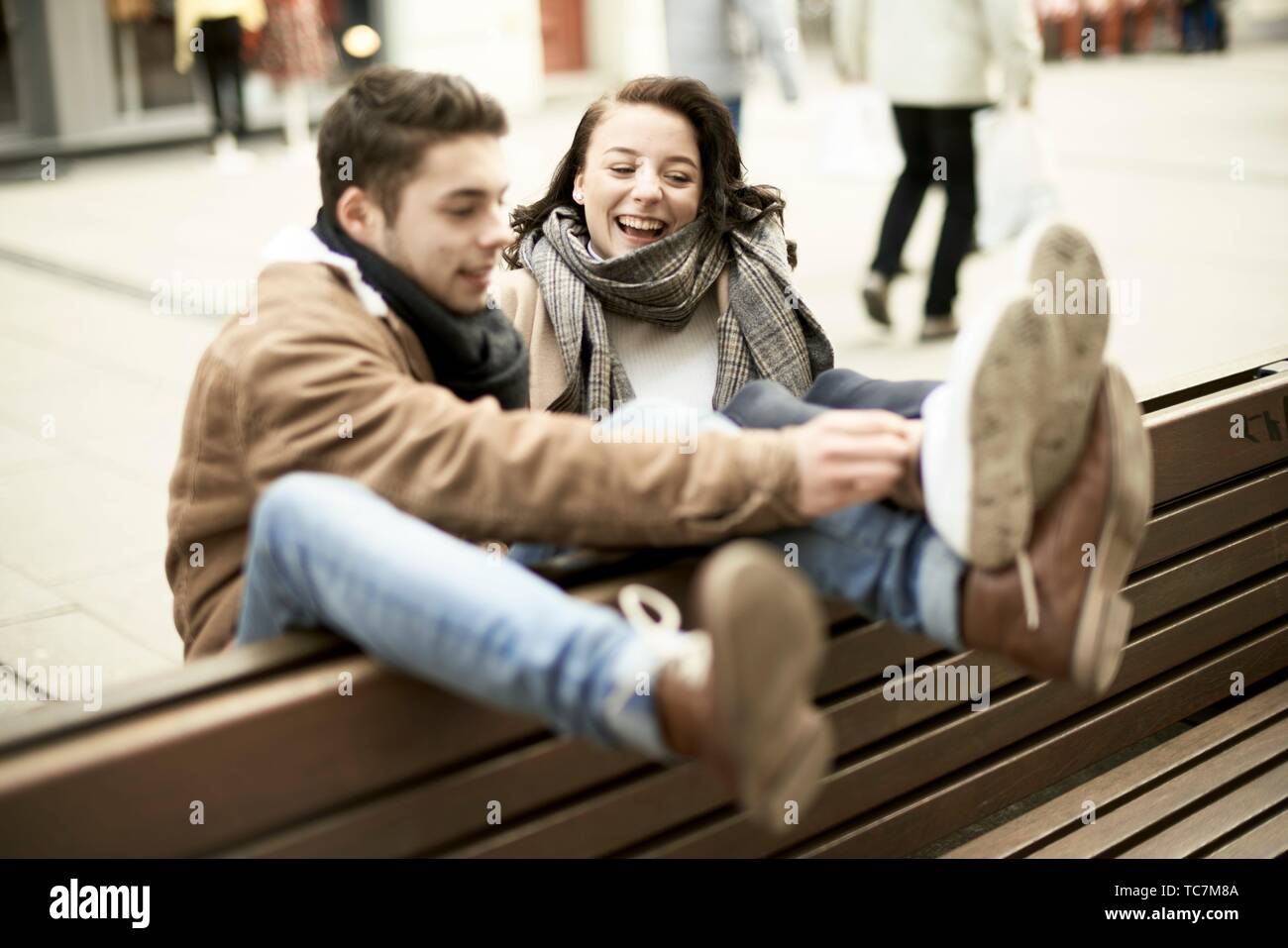 La pareja de adolescentes jóvenes sentados en un banco al revés en ciudad, colgando juntos, patas arriba, boca abajo, en Cottbus, Brandenburgo, Alemania Foto de stock