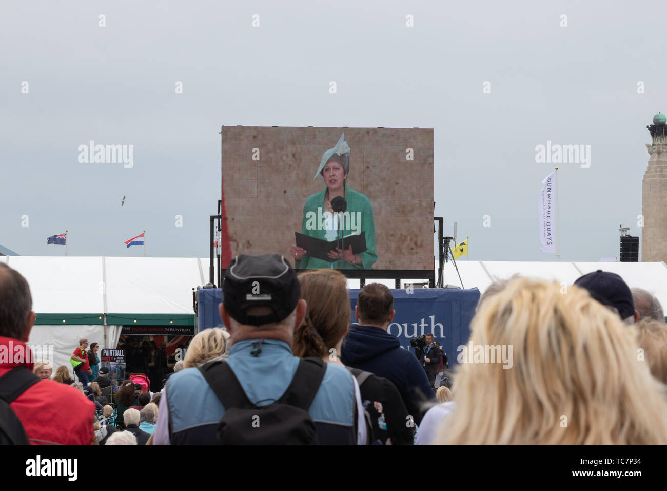 Una multitud mirando una pantalla grande como Teresa de mayo el primer ministro del Reino Unido, da un discurso durante el Día-D 75 conmemoraciones en Portsmouth Foto de stock