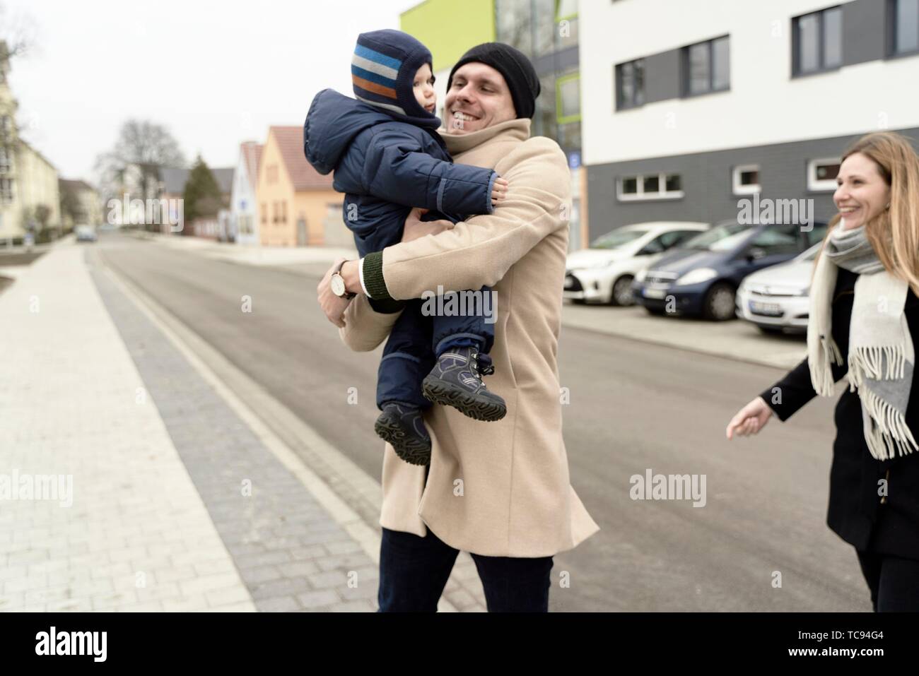 Los padres con el bebé niño niño caminando por la calle en la ciudad, familia, vistiendo ropa de invierno, en Cottbus, Brandenburgo, Alemania. Foto de stock