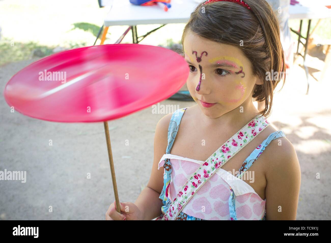 Cara pintada niño niña jugando con placa de hilado. Concepto de juguetes clásicos. Foto de stock