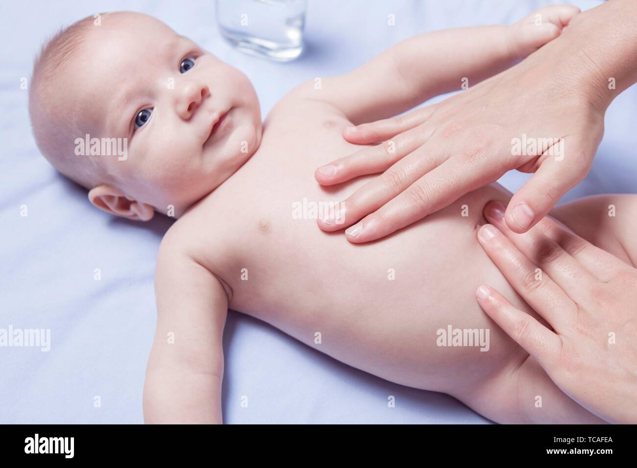 Masajes de abdomen a 3 mes Baby Boy. Terapeuta de masaje de manos femeninas. Foto de stock