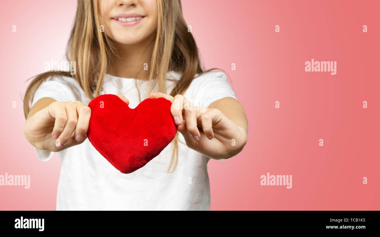 Bonita niña de la escuela en la camiseta blanca que muestra el símbolo del  corazón sobre fondo rojo Fotografía de stock - Alamy