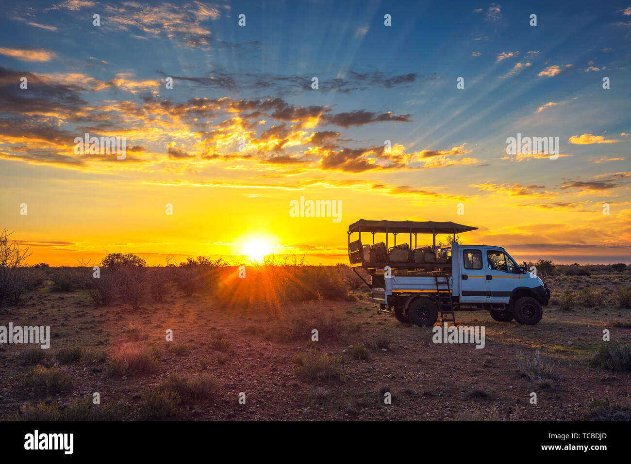 Safari africano se detiene el vehículo en el desierto de Kalahari para obtener un espectacular atardecer Foto de stock