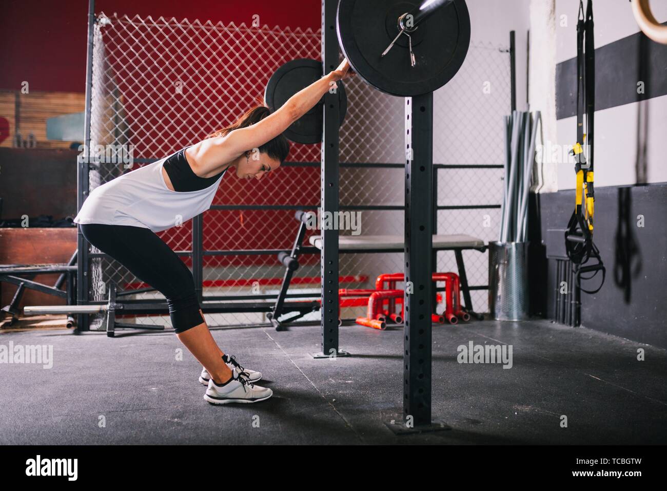 Athletic morena joven haciendo algunos ejercicios de levantamiento de pesas. Foto de stock