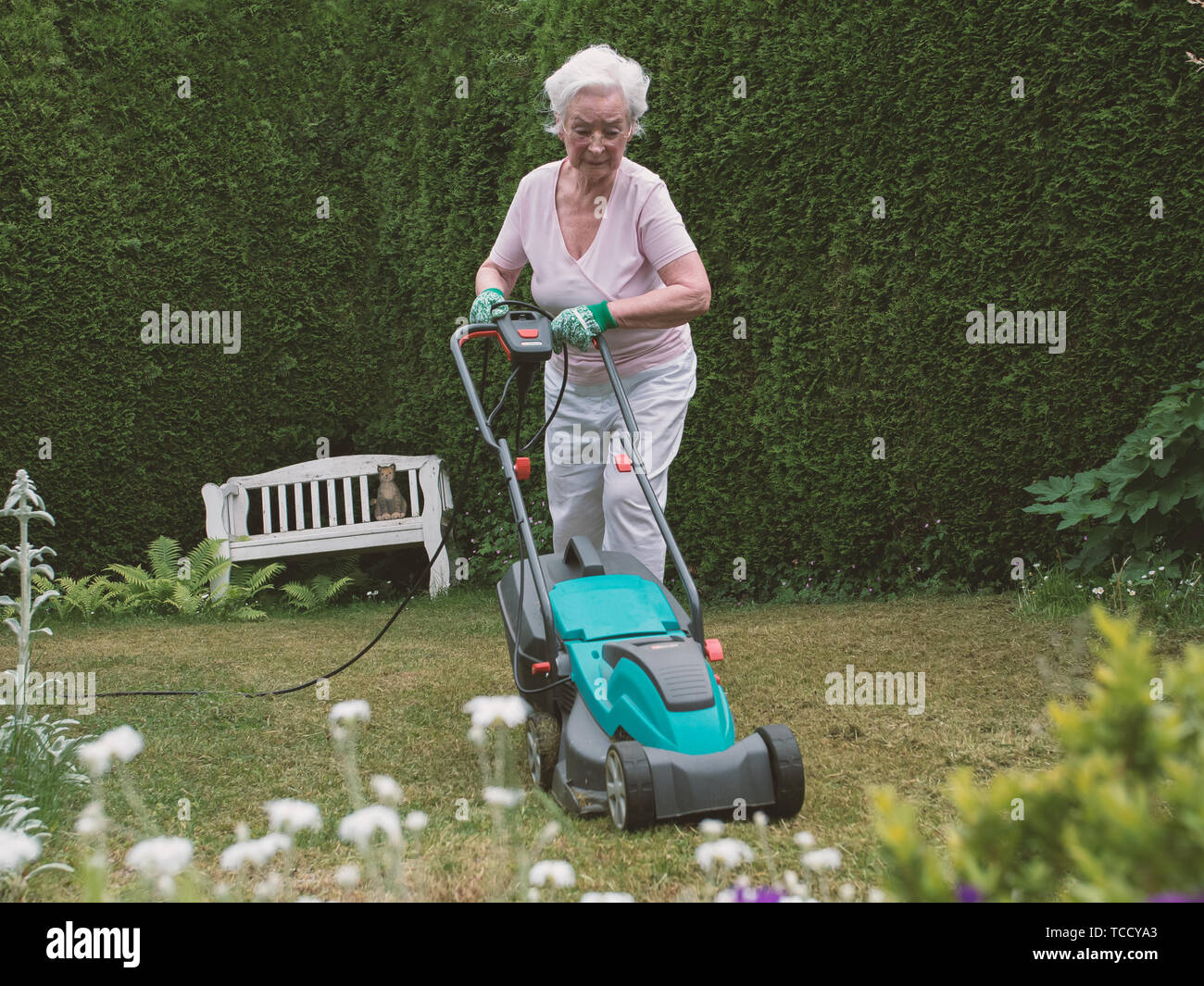 Senior mujer trabajando en el jardín con la segadora Foto de stock