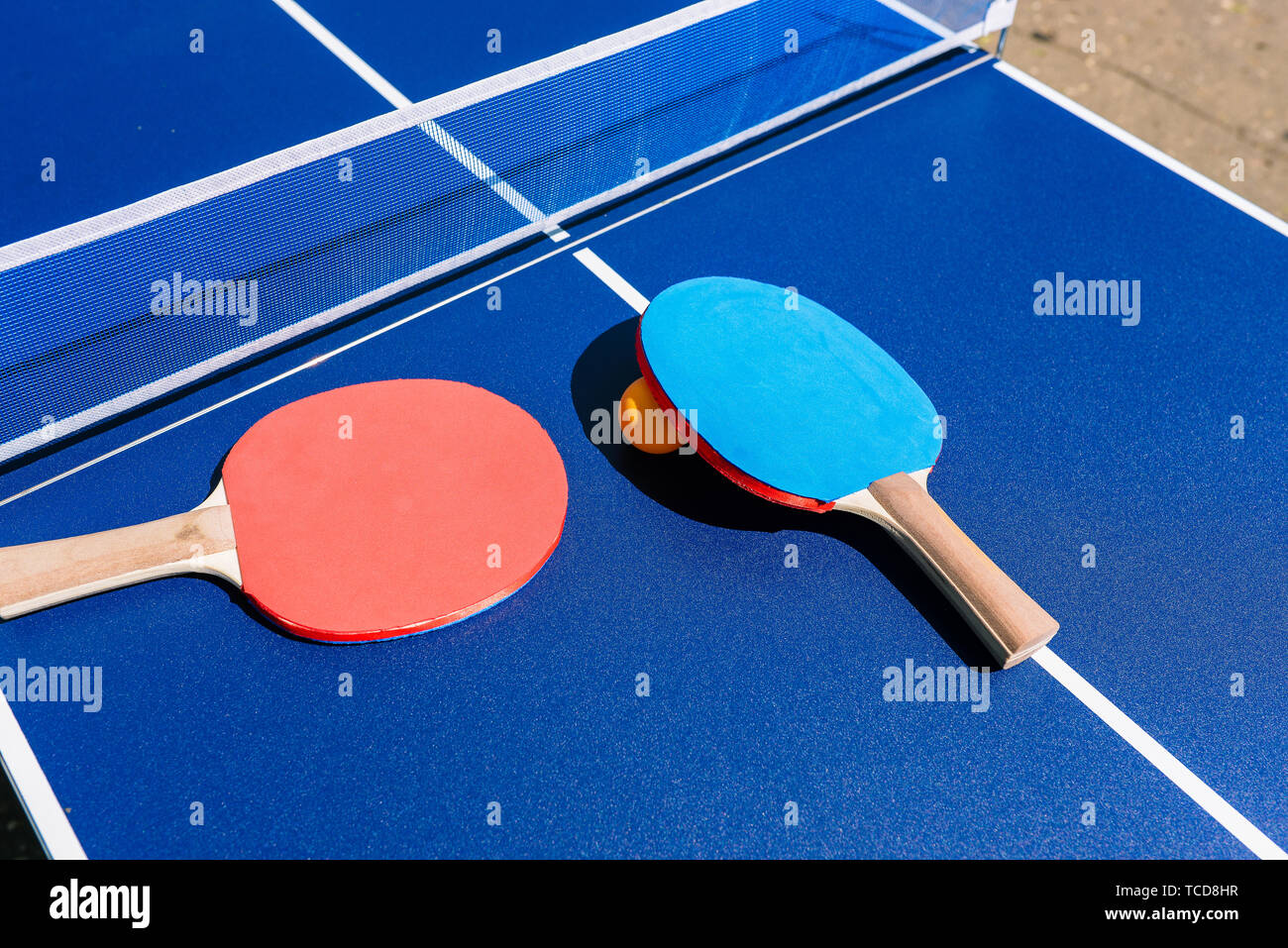 atravesar región fuego Tabla y raquetas para jugar al tenis de mesa o ping-pong. Tabla azul con  malla blanca y azul y rojo raquetas. Orange Ball Fotografía de stock - Alamy
