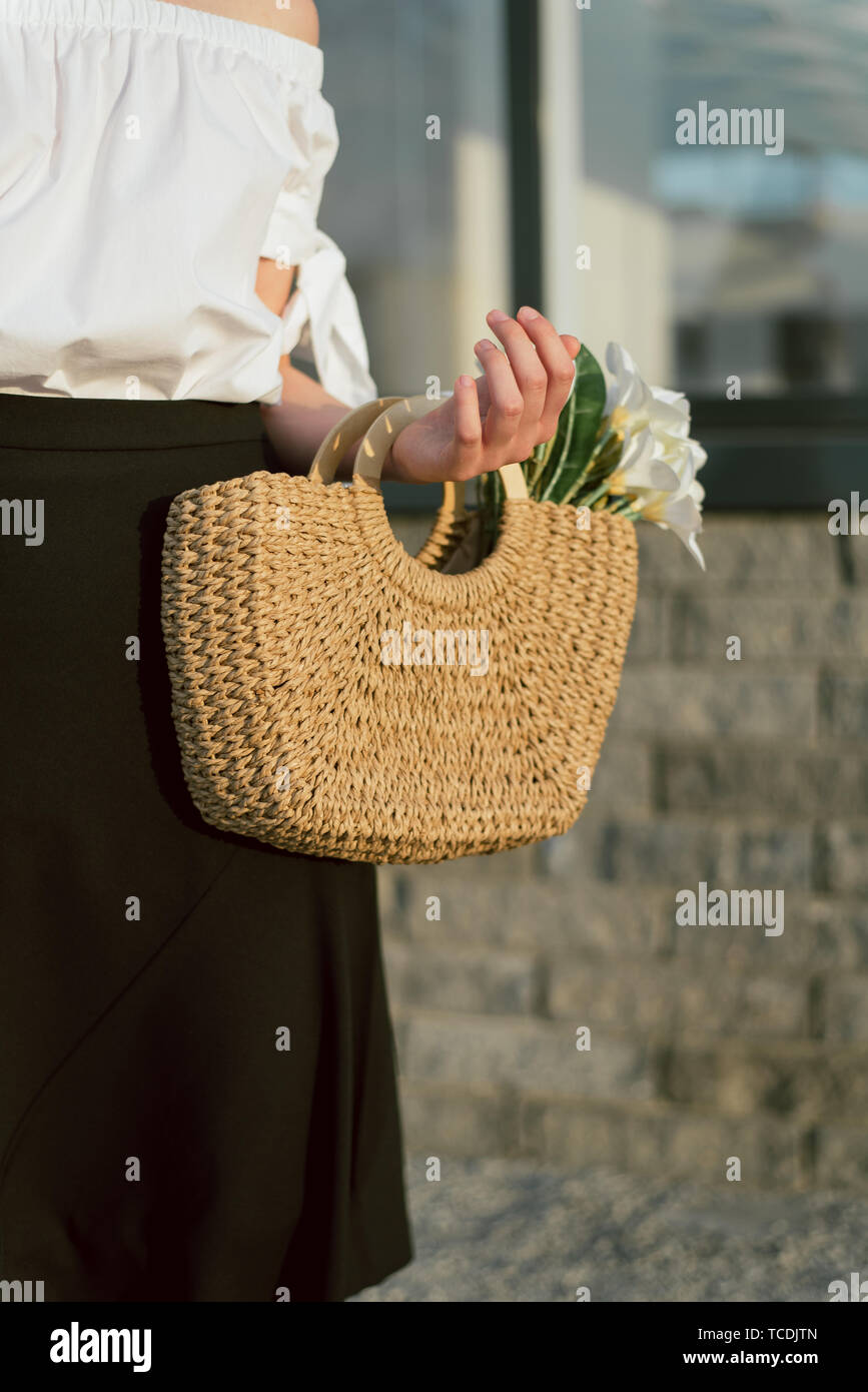 Bolsa mimbre en la mano de joven chica con una de paja de beige en el paisaje urbano Fotografía de stock - Alamy
