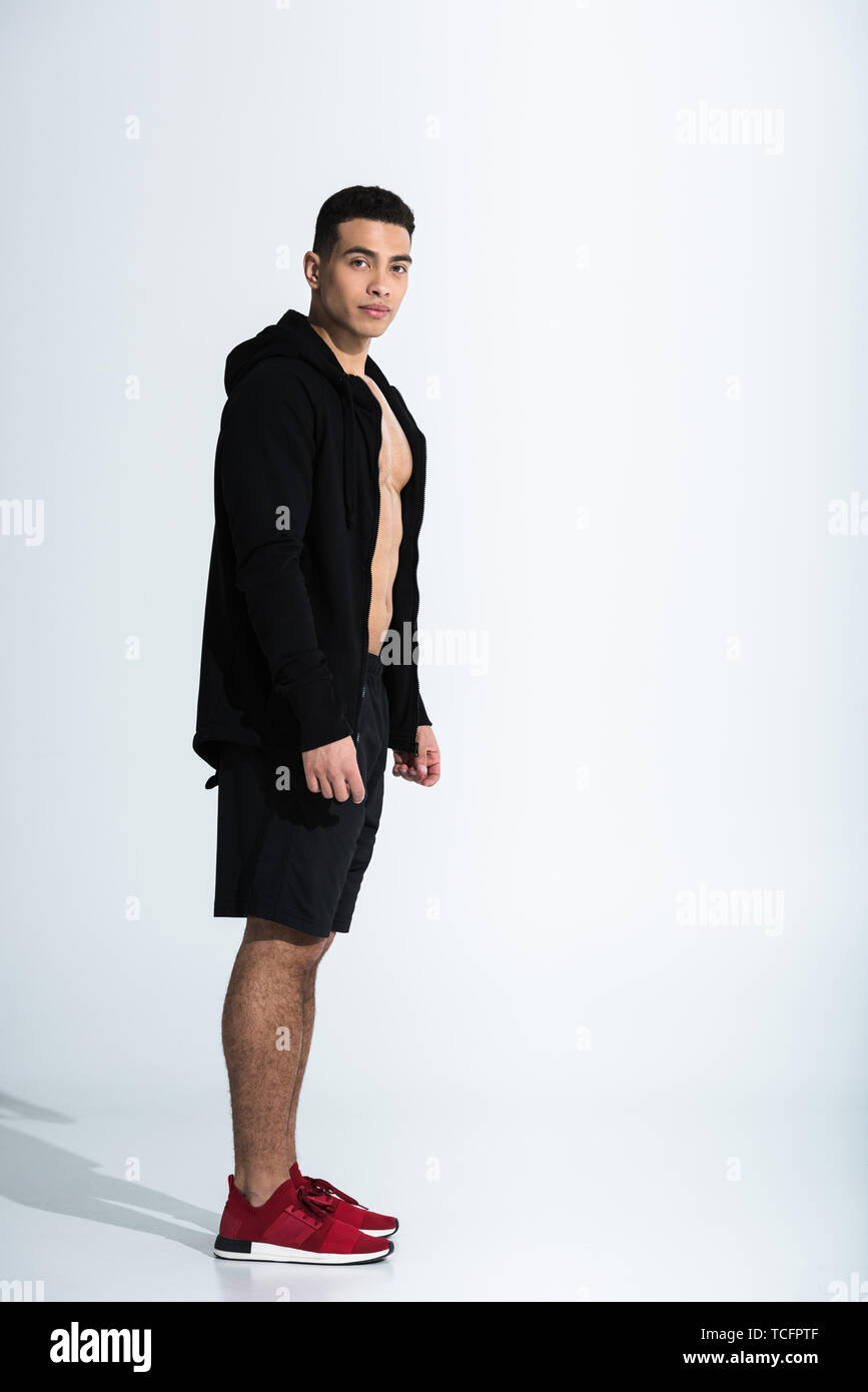 Guapo de raza mixta deportiva hombre de negro la ropa y zapatillas rojas  mirando a la cámara en blanco Fotografía de stock - Alamy