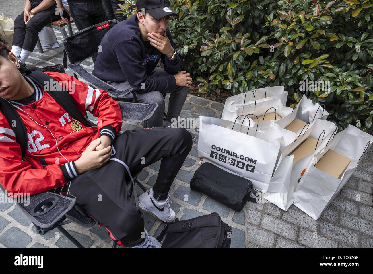 Barcelona, Cataluña, España. El 7 de junio de 2019. Dos hombres jóvenes  sentados con sus bolsas de compras que contiene el nuevo Adidas Yeezy Boost  350 modelo de zapato diseñado por Kanye