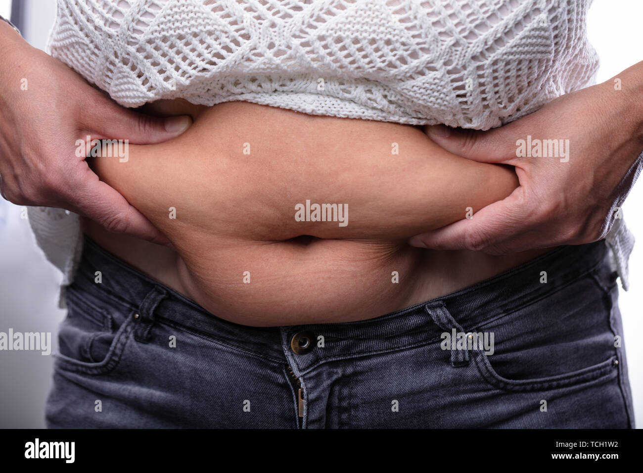 Close-up de mujer pellizcando la grasa del vientre con sus dos manos Foto de stock