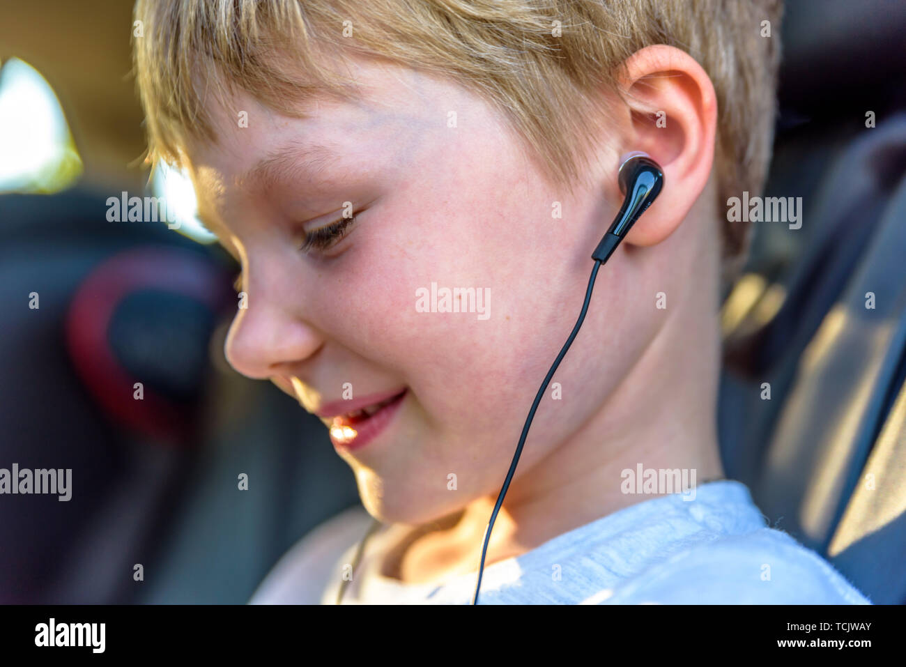 Niño con auriculares dentro del coche viendo la película o escuchando  música en su smartphone Fotografía de stock - Alamy