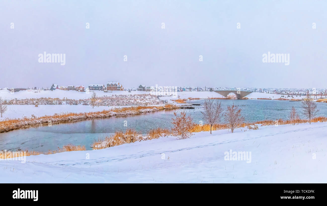 Panorama idílico paisaje invernal con un tranquilo lago plateado en medio de un paisaje cubierto de nieve Foto de stock