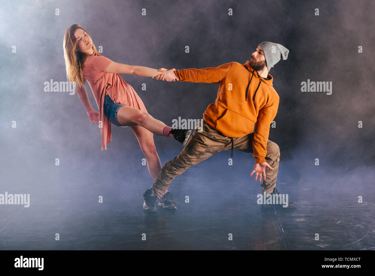 Pareja bailando la danza moderna y mostrando pierna estirada mueve.fondo mientras que la pareja está vestida con ropa de colores urbanos Fotografía de stock - Alamy