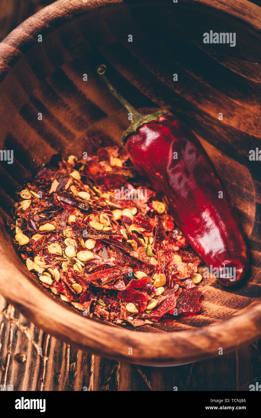 Los copos de pimiento rojo de tierra en el tazón de madera Foto de stock
