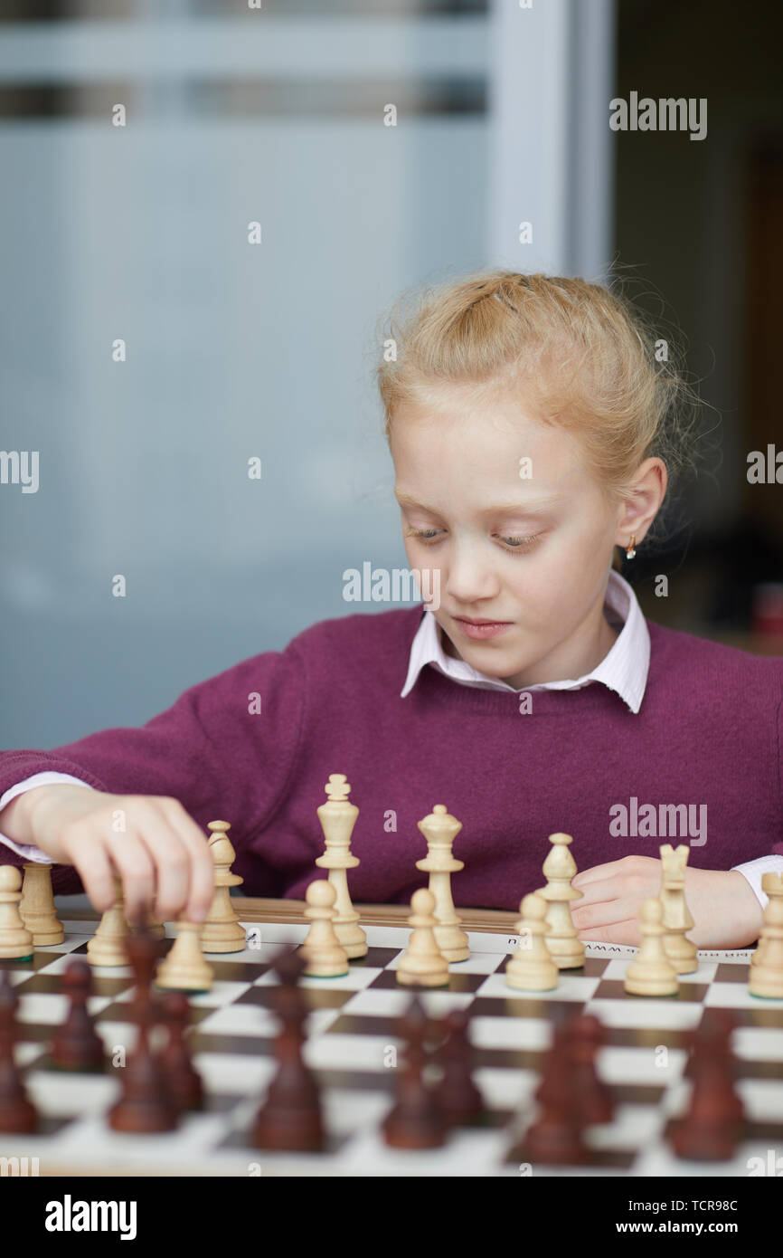 Chica con pelo rojo trenzado en color púrpura suéter estudiando las figuras  de ajedrez y cómo pueden mover Fotografía de stock - Alamy