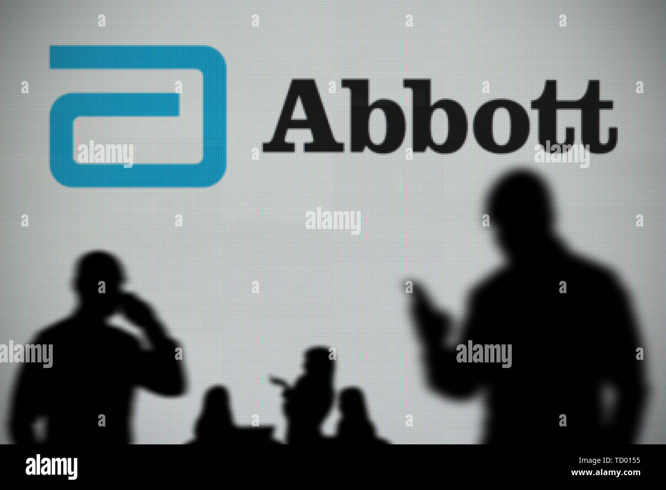 Los laboratorios Abbott logo es visto en una pantalla LED en el fondo mientras una silueta persona utiliza un smartphone en primer plano (uso Editorial Foto de stock
