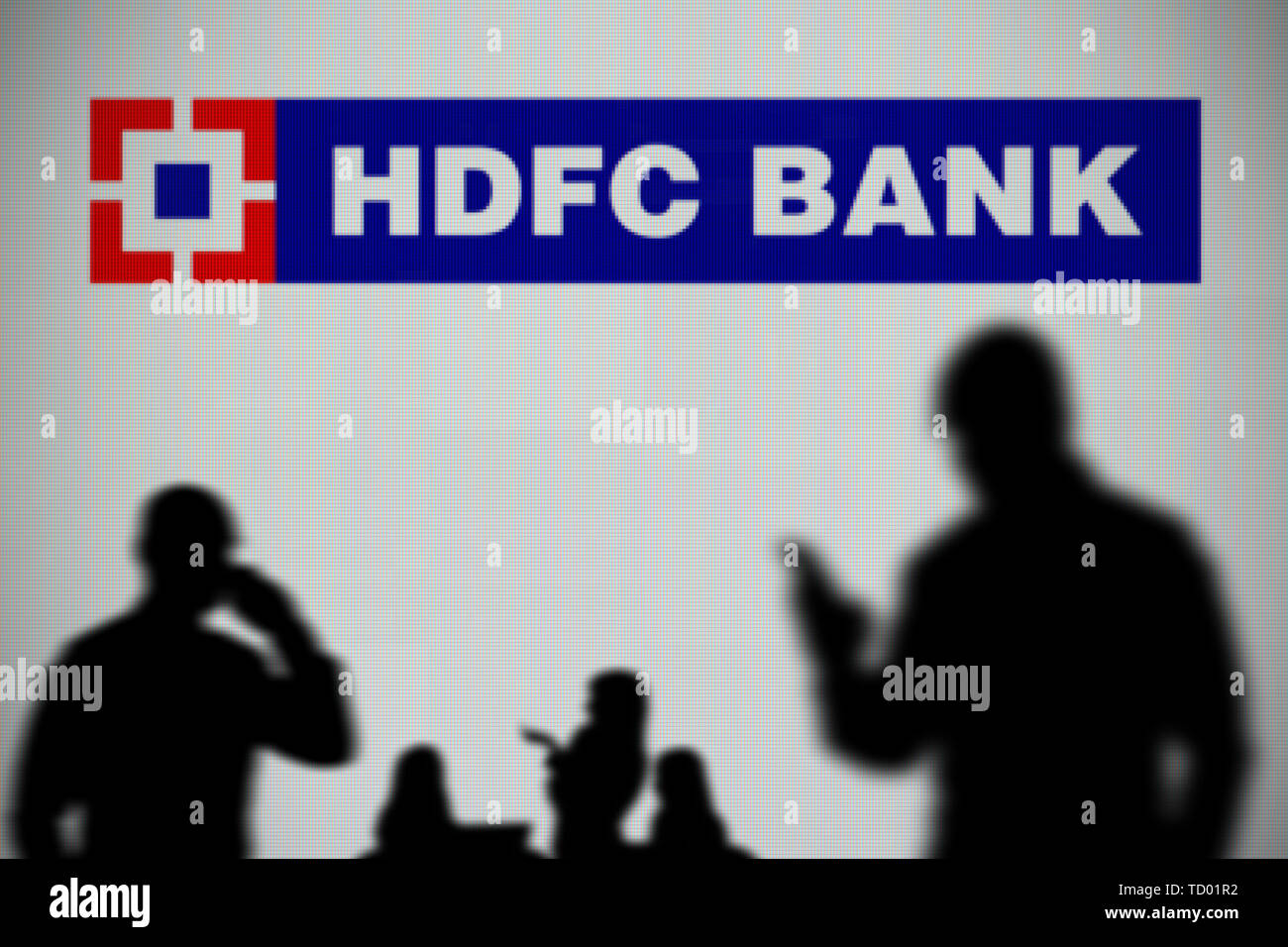 El HDFC Bank logo es visto en una pantalla LED en el fondo mientras una silueta persona utiliza un smartphone en primer plano (uso Editorial solamente) Foto de stock