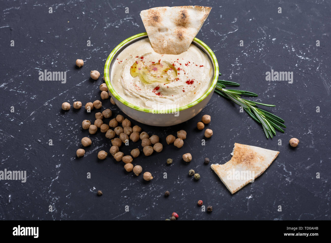 Hummus casero, garbanzos, frijoles, Rosemary con pita en black mesa de piedra. La cocina árabe tradicional de Oriente Medio. Foto de stock