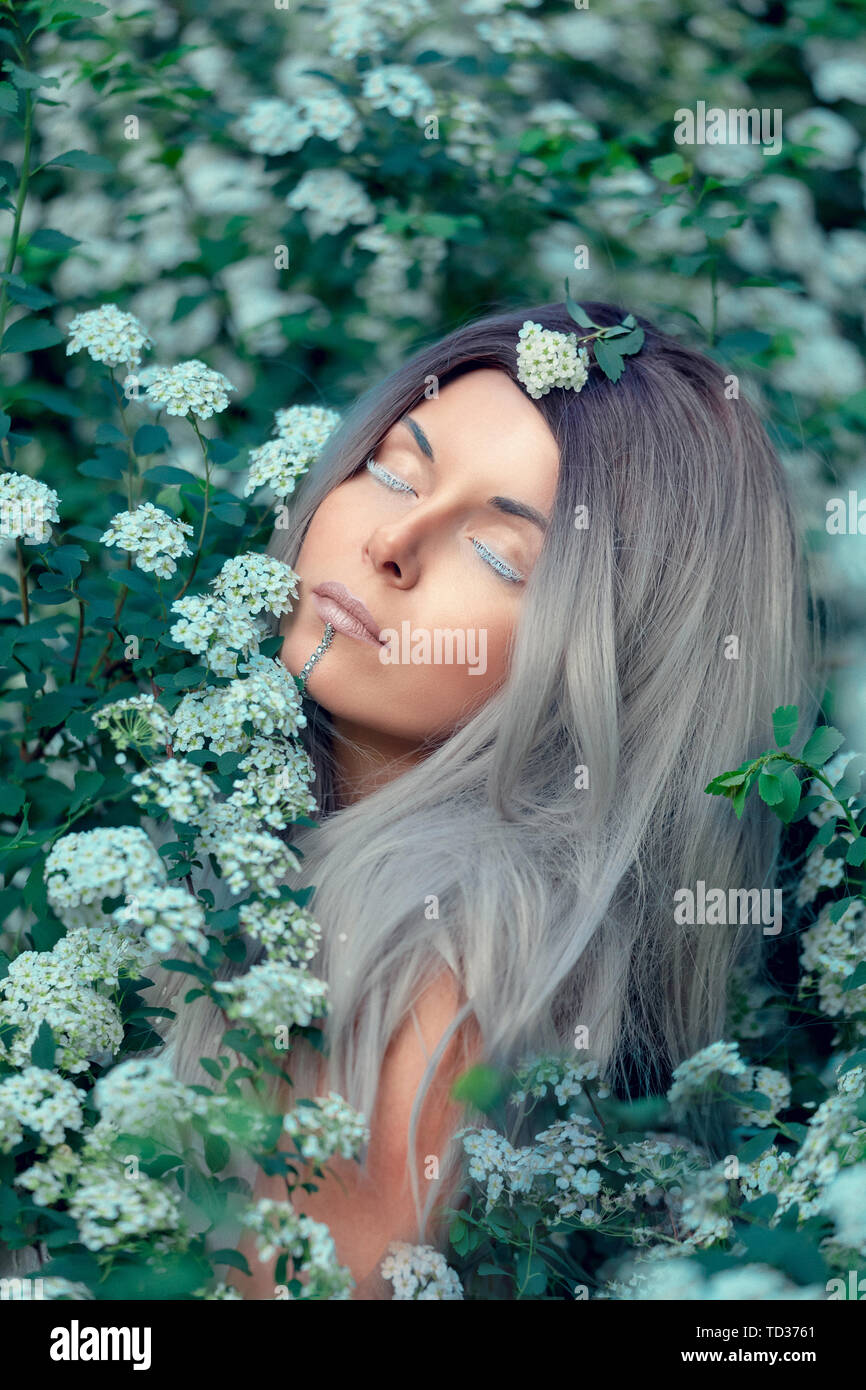 Fairy Tail ninfa del bosque, hermosa mujer sexy con el cabello blanco de spring garden, sentados en flor, árbol vintage estilo de moda de ensueño Foto de stock