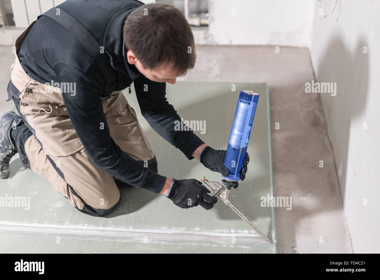 El trabajador es usar una espuma de poliuretano para el encolado de yeso en  noventa grados. Mano sujetando la expansión de espuma de poliuretano  aplicador Pistola de pegamento Fotografía de stock -