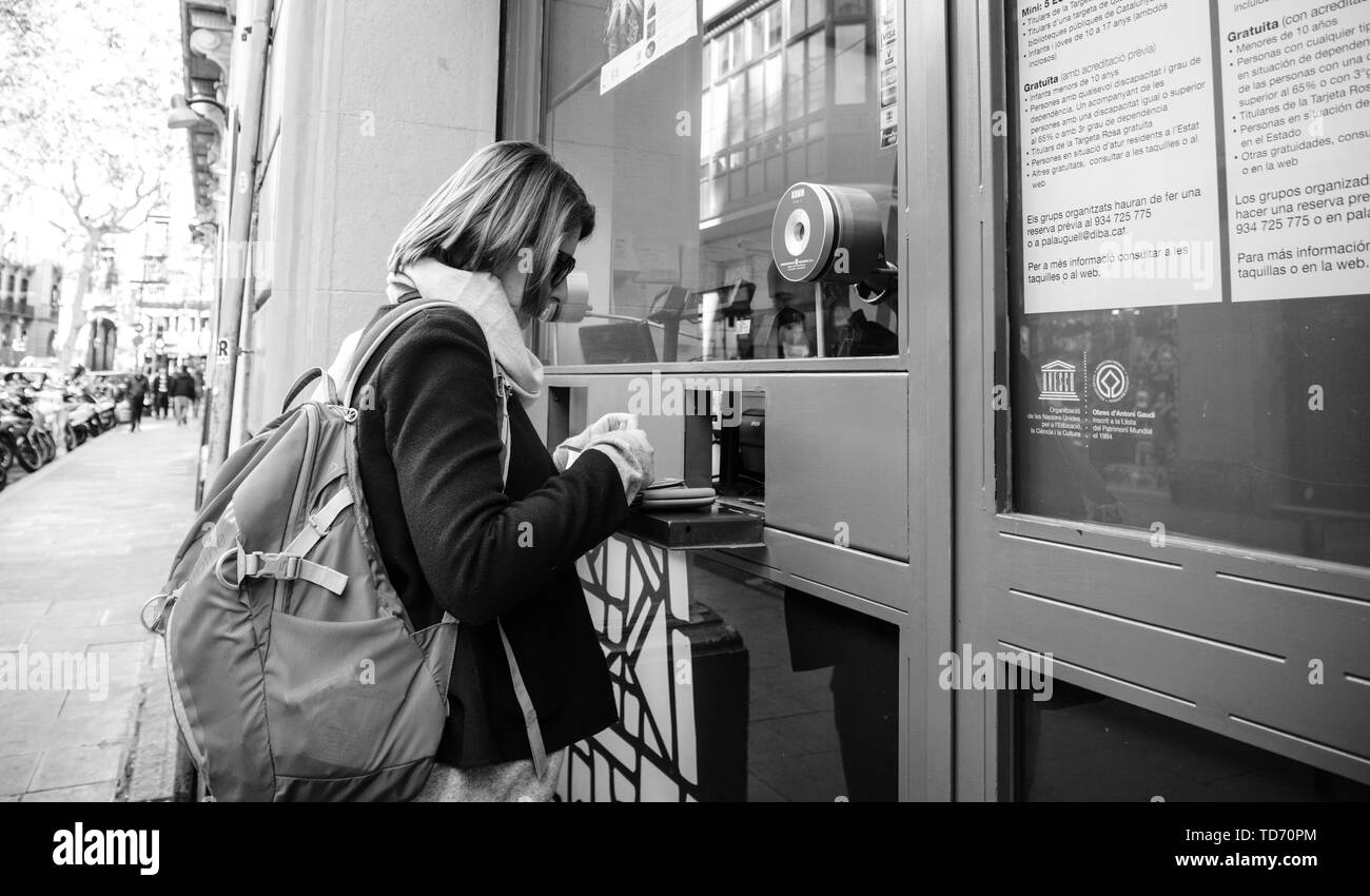 Barcelona, España - 14 Nov, 2017: imagen en blanco y negro de Street View de joven mujer turista comprar los billetes en el mostrador del Palau Güell situado j Foto de stock