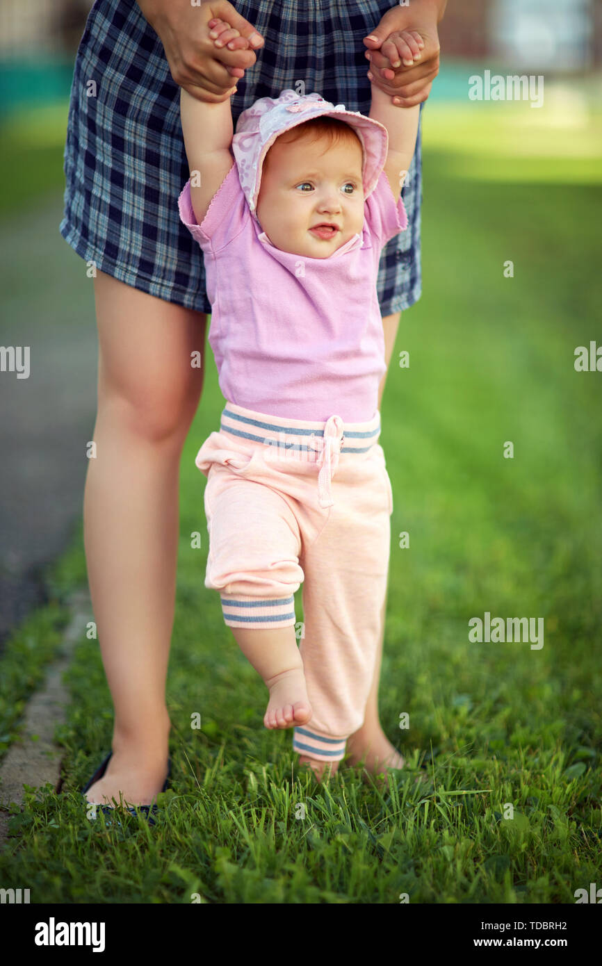 Madre enseñar a su bebé a dar los primeros pasos descalzo sobre el césped  Fotografía de stock - Alamy