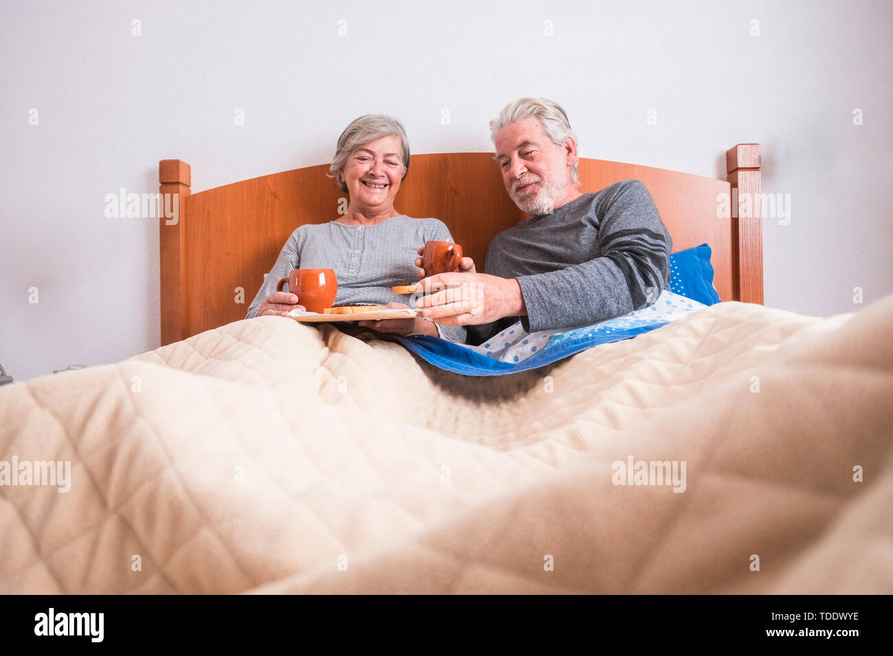 Edad caucásico par hacer el desayuno en casa en la cama. bonito escenario natural en el hogar para la vida togheterness concepto. amor y despreocupada de personas casadas. Foto de stock
