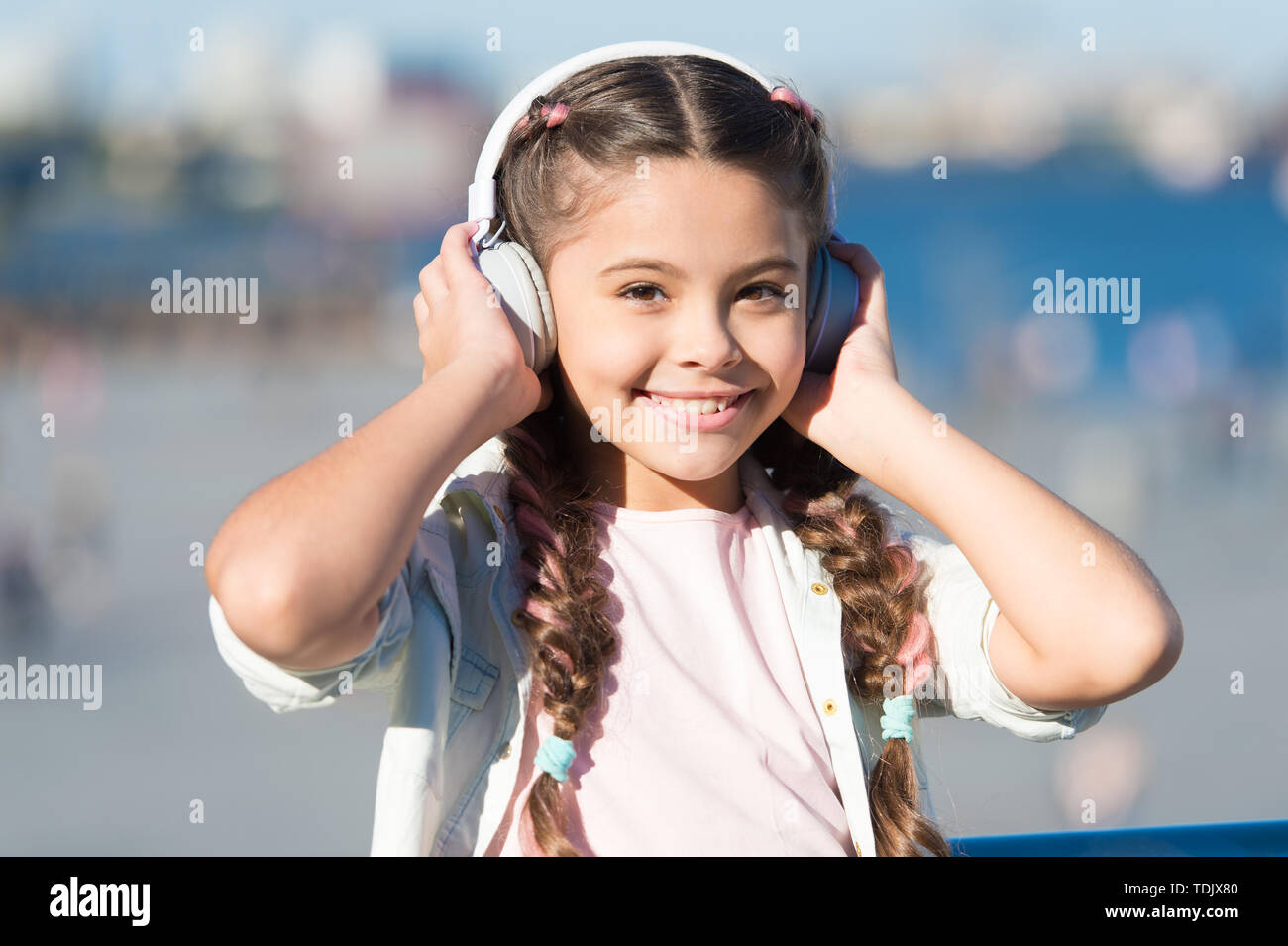 Ir con el flujo. Adorable usuario auriculares. Los niños pequeños vestidos  de blanco ajustable auriculares. Niña con auriculares inalámbricos con  Bluetooth en el exterior. Cute kid escuchando música con auriculares  estéreo Fotografía