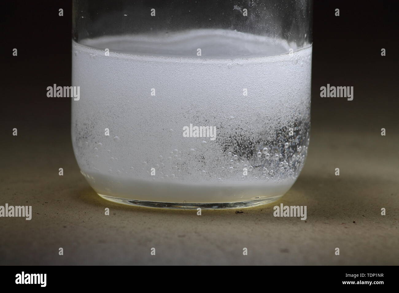 Primer plano de un vinagre y bicarbonato de sodio reacción ocurre en el fondo de un tarro de vidrio; vinagre borrado de burbujas. Foto de stock