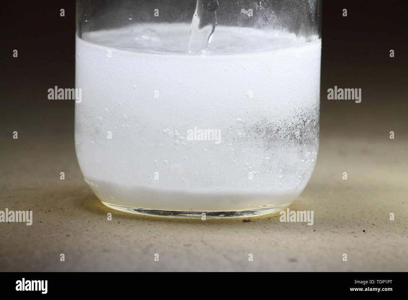 Primer plano de un vinagre y bicarbonato de sodio reacción ocurre en el fondo de un tarro de vidrio Foto de stock