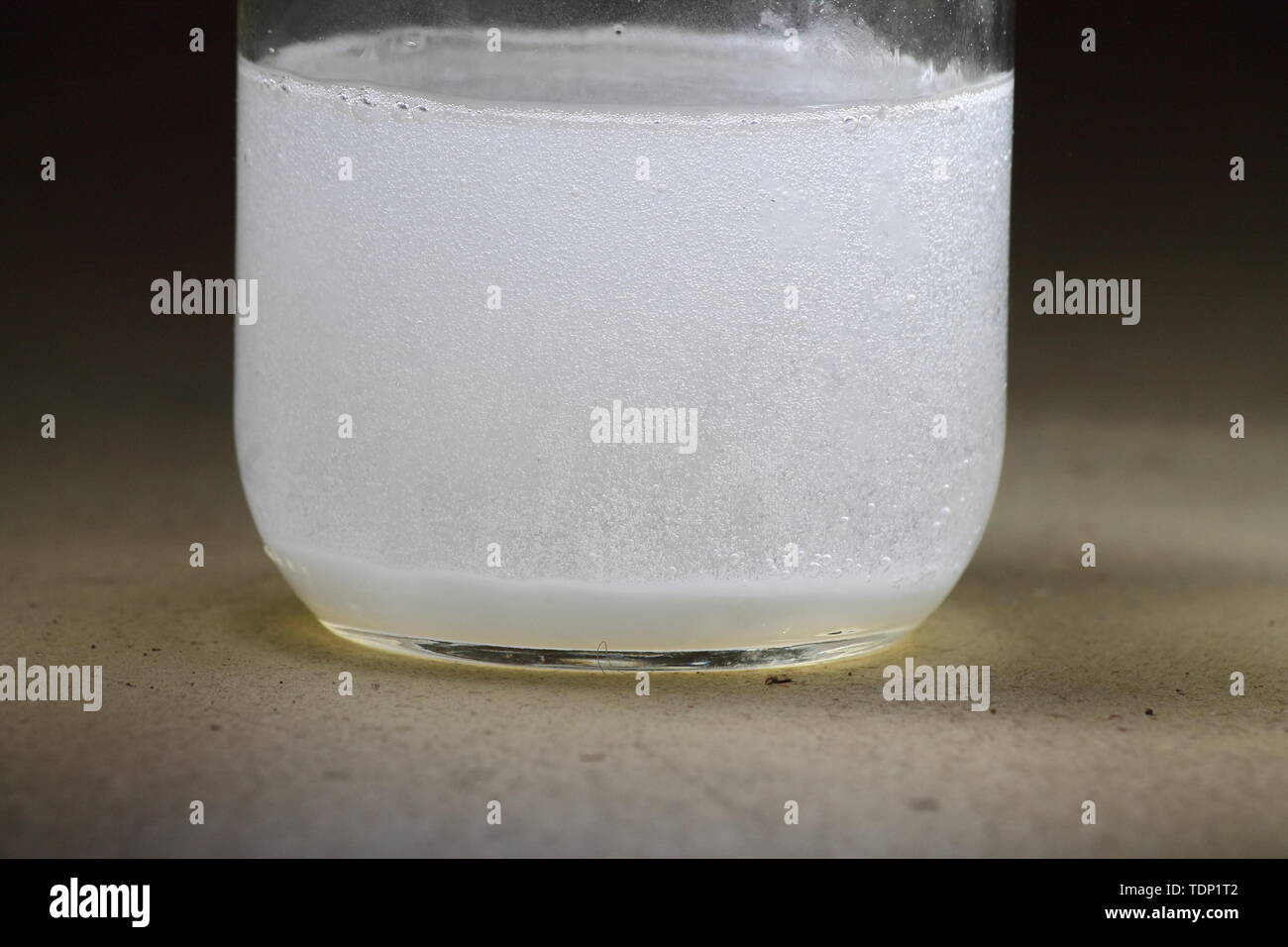 Primer plano de un vinagre y bicarbonato de sodio reacción ocurre en el fondo de un tarro de vidrio; solución turbia Foto de stock